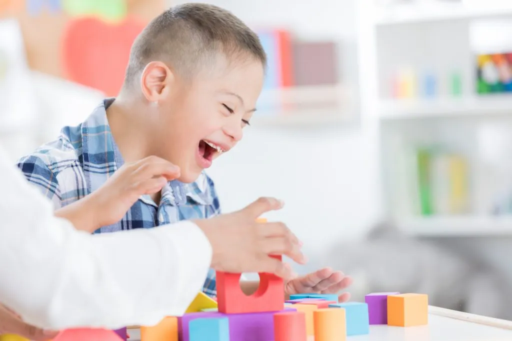Teacher helps young boy with blocks