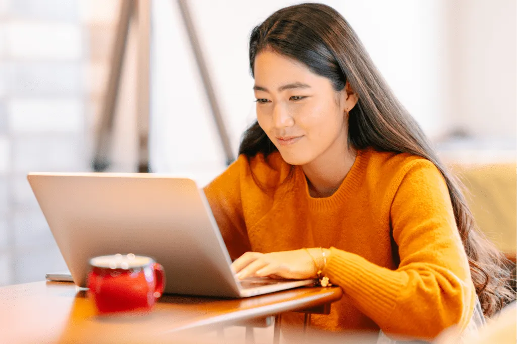 Teacher reading on her laptop with a cup of coffee